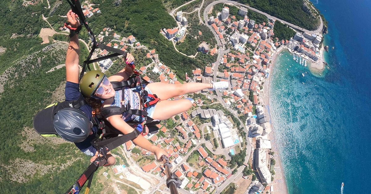 Happy woman smiling during a tandem paragliding flight over Bečići beach and the Adriatic coast, Budva Riviera.