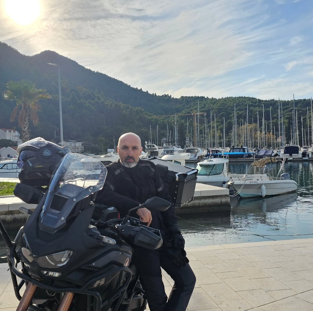 Paragliding pilot Fahrudin Gjokaj on his Honda Africa Twin adventure bike in a marina, Montenegro.
